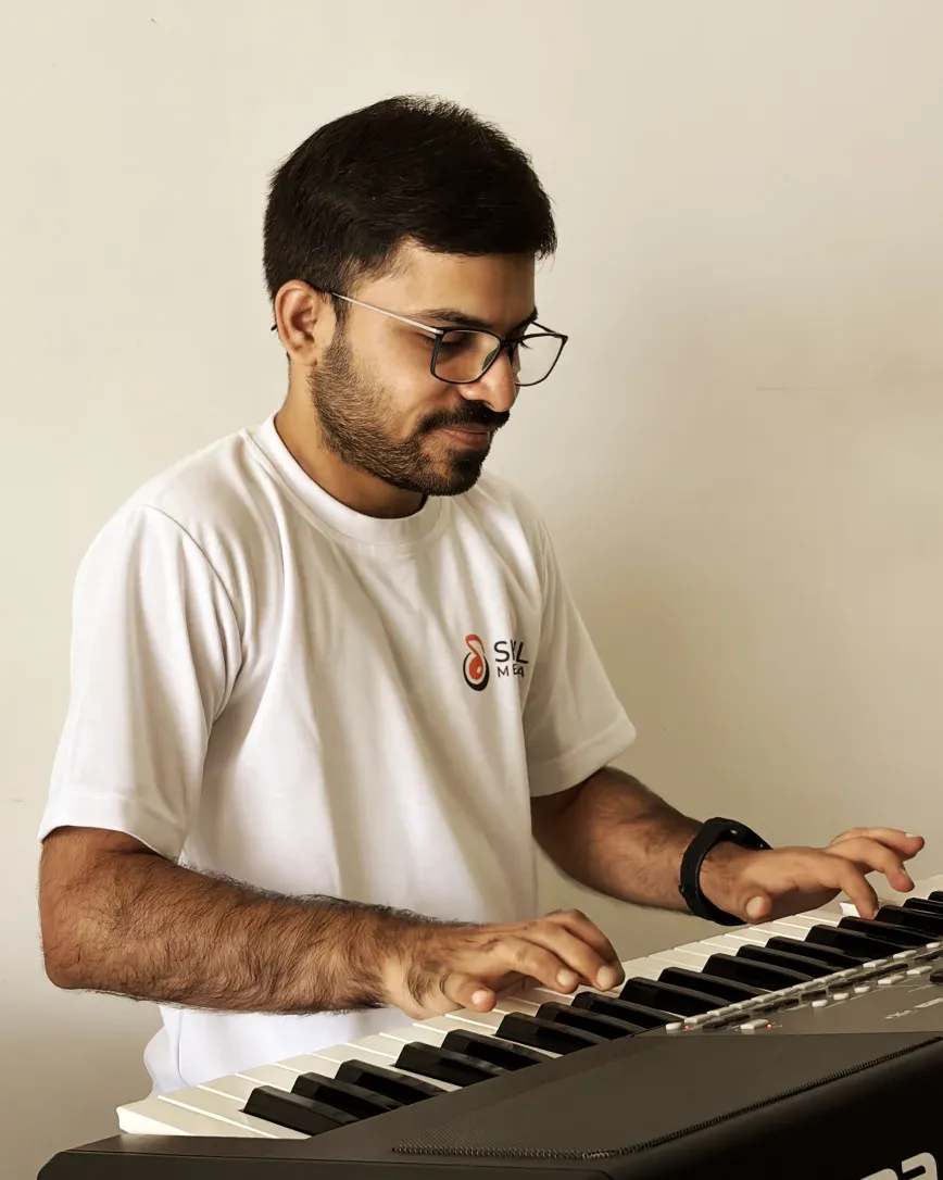 Shail Mewada playing the electronic keyboard, wearing his music academy t-shirt