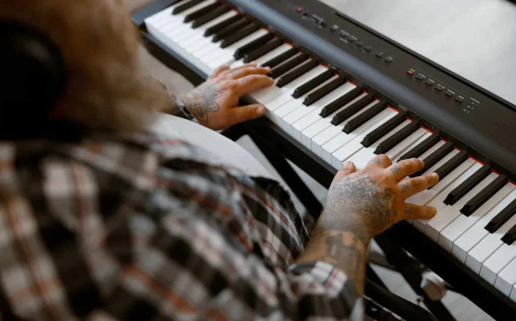 A pianist reading from sheet music while playing a digital piano with both hands